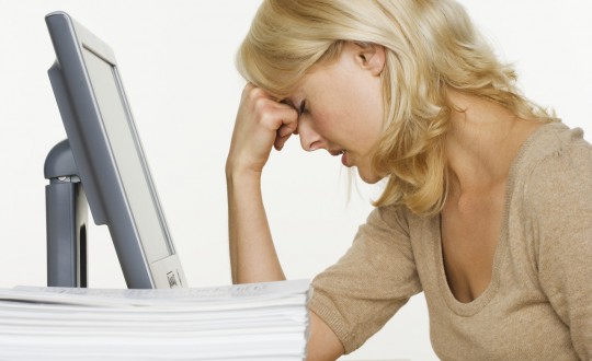 Frustrated Woman at Computer With Stack of Paper